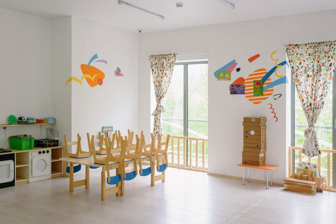 A bright, freshly cleaned kindergarten room with wooden chairs neatly arranged around a table