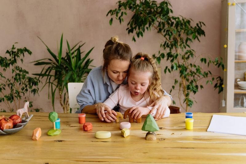 An adult holding a young child close as they play with wooden shapes at a table